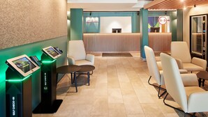 A hotel lobby with a reception desk, self-check-in kiosks, seating area, and a modern design with wooden accents. - B&B Hotel Frankfurt-Niederrad (Frankfurt)
