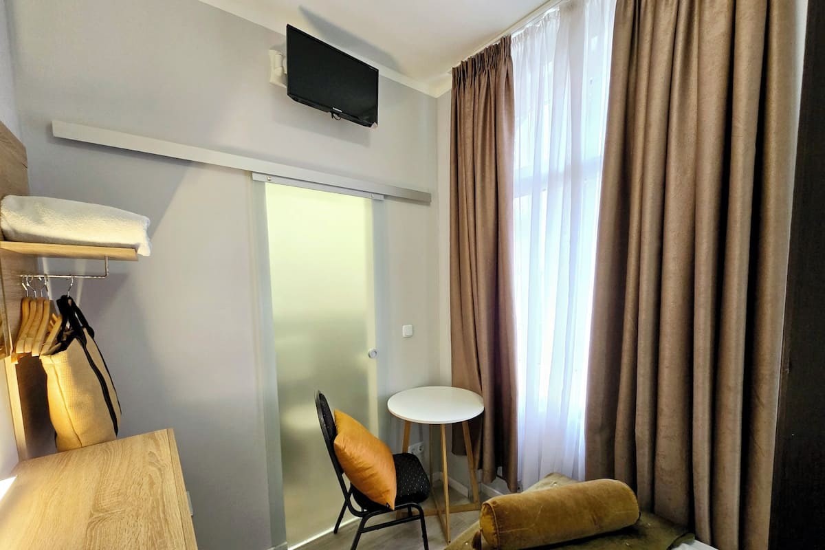 A hotel room with a bed, a small round table, a chair, a TV mounted on the wall, and a sliding door.
