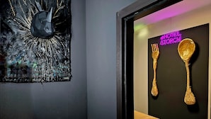 A modern interior with a dark wall, a neon sign reading "HOTEL STORCH", and two golden utensils hanging on the wall. - City Hotel Storch (Cologne)