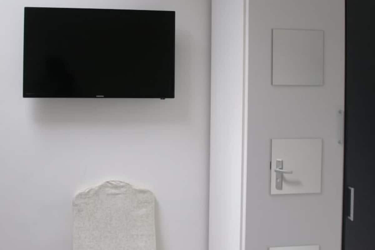 A bathroom with a black toilet, a white sink, and a towel hanging on the wall.