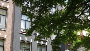 A row of townhouses with a green awning, a parked car, and a sign indicating a car park. - Hotel Kap (Amsterdam)