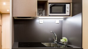 A modern kitchen with a built-in microwave, stainless steel sink, and a small countertop area. - Bonanova Suite Hotel (Barcelona)