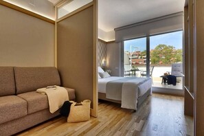 Une chambre d’hôtel avec un canapé, un lit, une petite table et une vue sur l’extérieur.