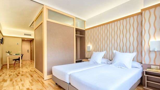 A hotel room with a large bed, a desk, and a wardrobe. - Bonanova Suite Hotel (Barcelona)