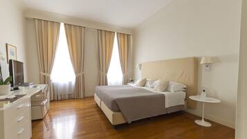A modern bedroom with a large bed, bedside tables, a desk, and a chair.
