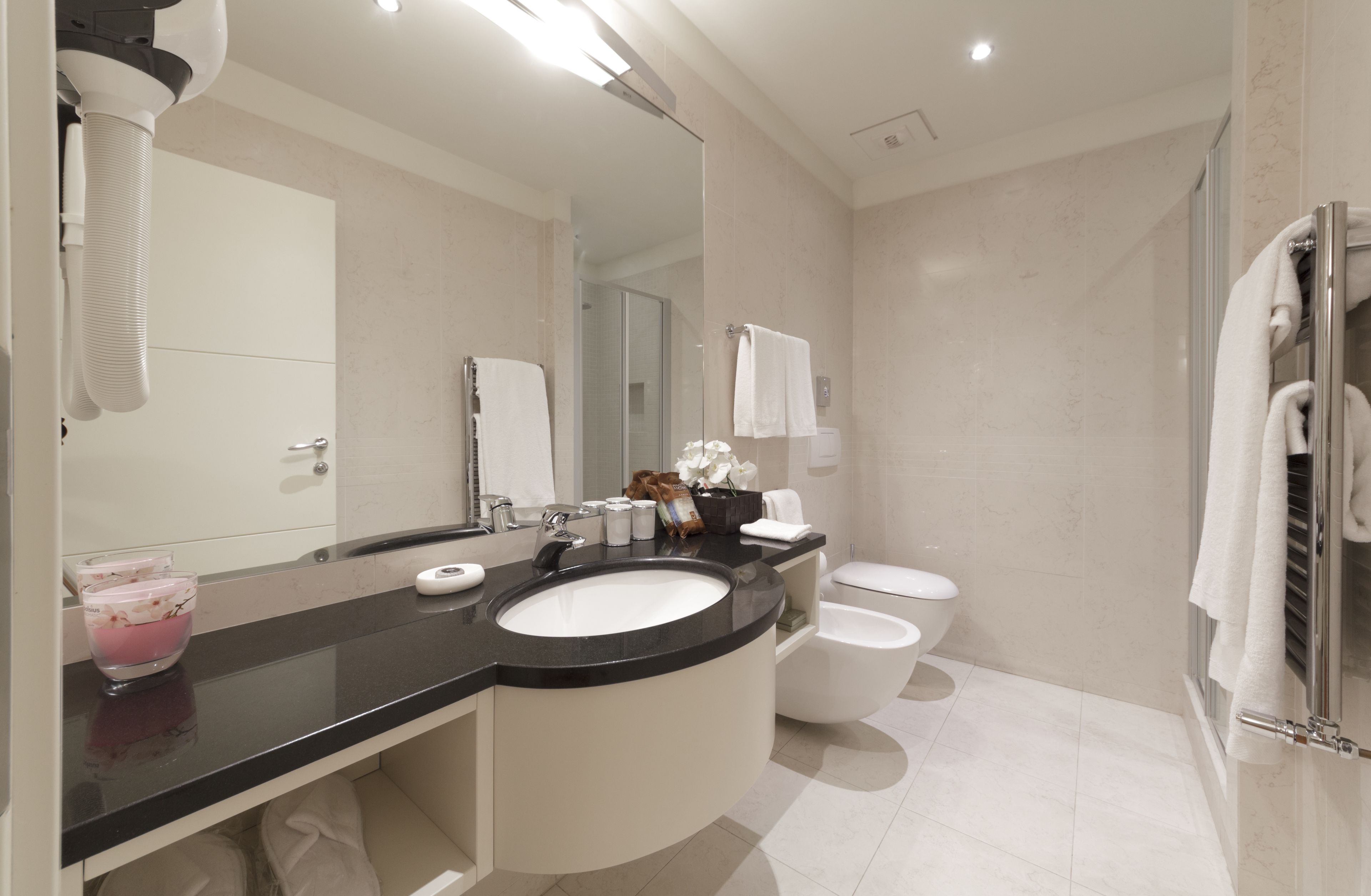 A modern bathroom with a black countertop sink, a glass shower enclosure, and a white toilet.