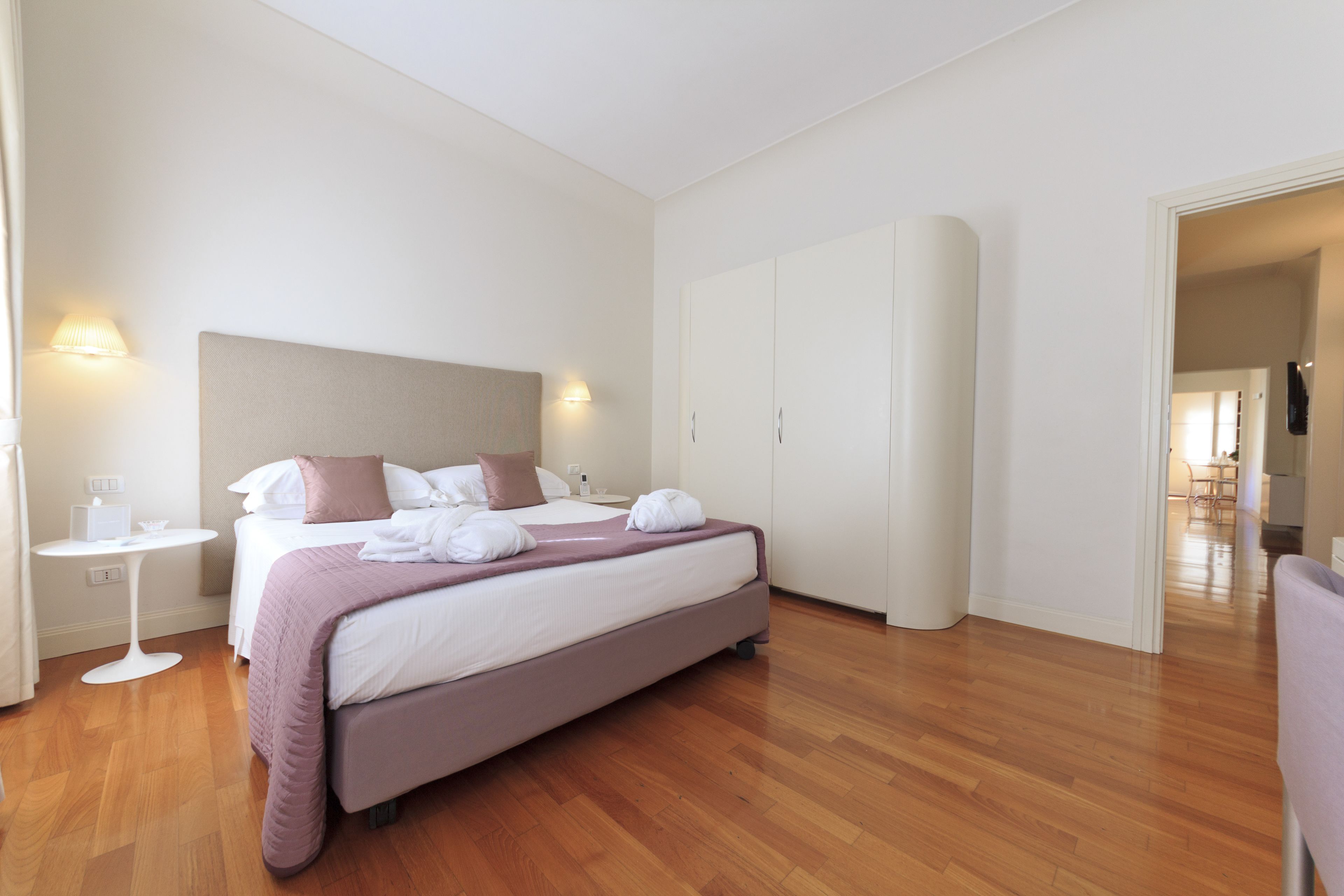 Une chambre d’hôtel moderne, dotée d’un grand lit, de tables de chevet et d’une armoire.