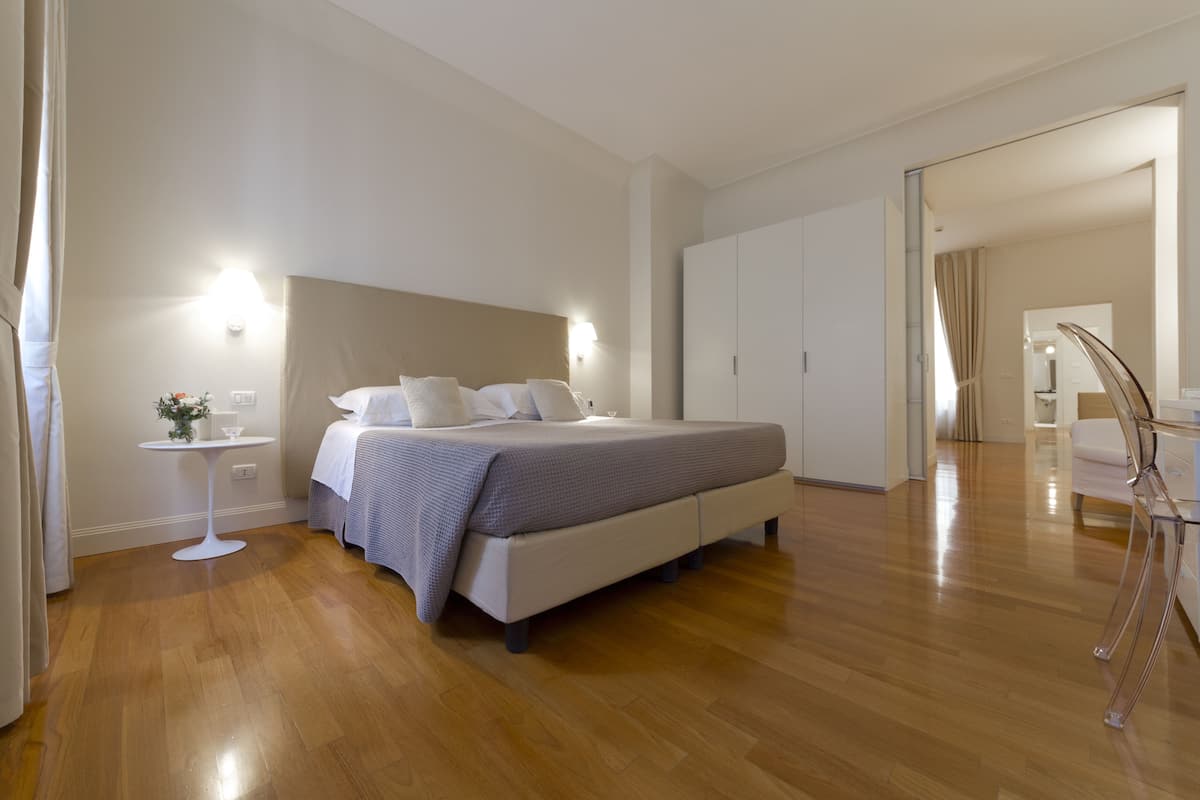A modern bedroom with a large bed, bedside tables, and a wardrobe.