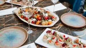 Una mesa de comedor lista con platos de comida, vasos y cubiertos.