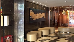 A lobby with a checkered floor, a large abstract wall art, and a seating area with round ottomans. - Insail Hotels (Guangyuanxincun Jingtai Pedestrian Street Guangzhou) (Guangzhou)