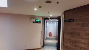 A hotel corridor with a wooden wall on the right, a sign indicating room numbers 1106-1110, and a fire extinguisher in the distance. - Insail Hotels (Guangyuanxincun Jingtai Pedestrian Street Guangzhou) (Guangzhou)