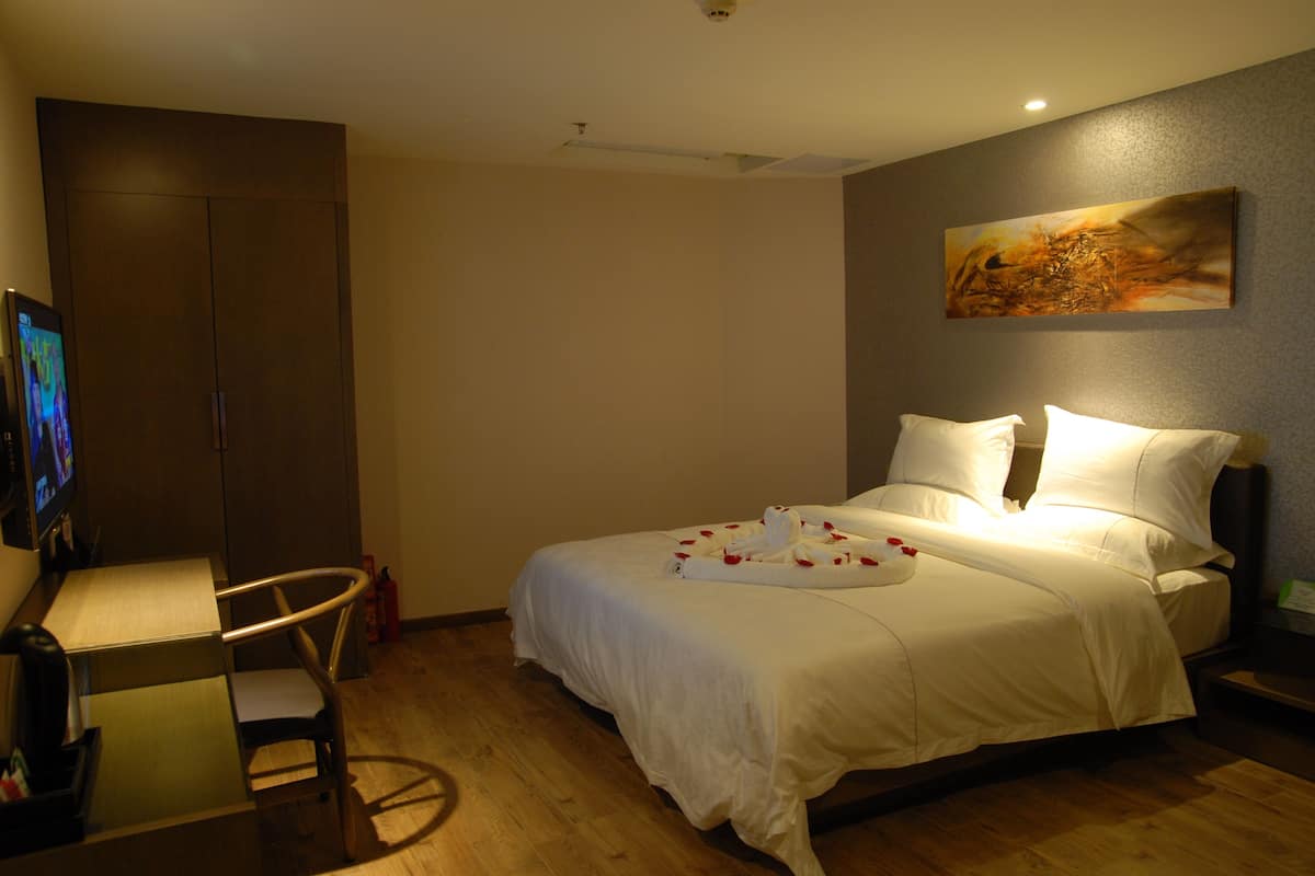 A hotel room with a bed, a desk, a chair, and a television.