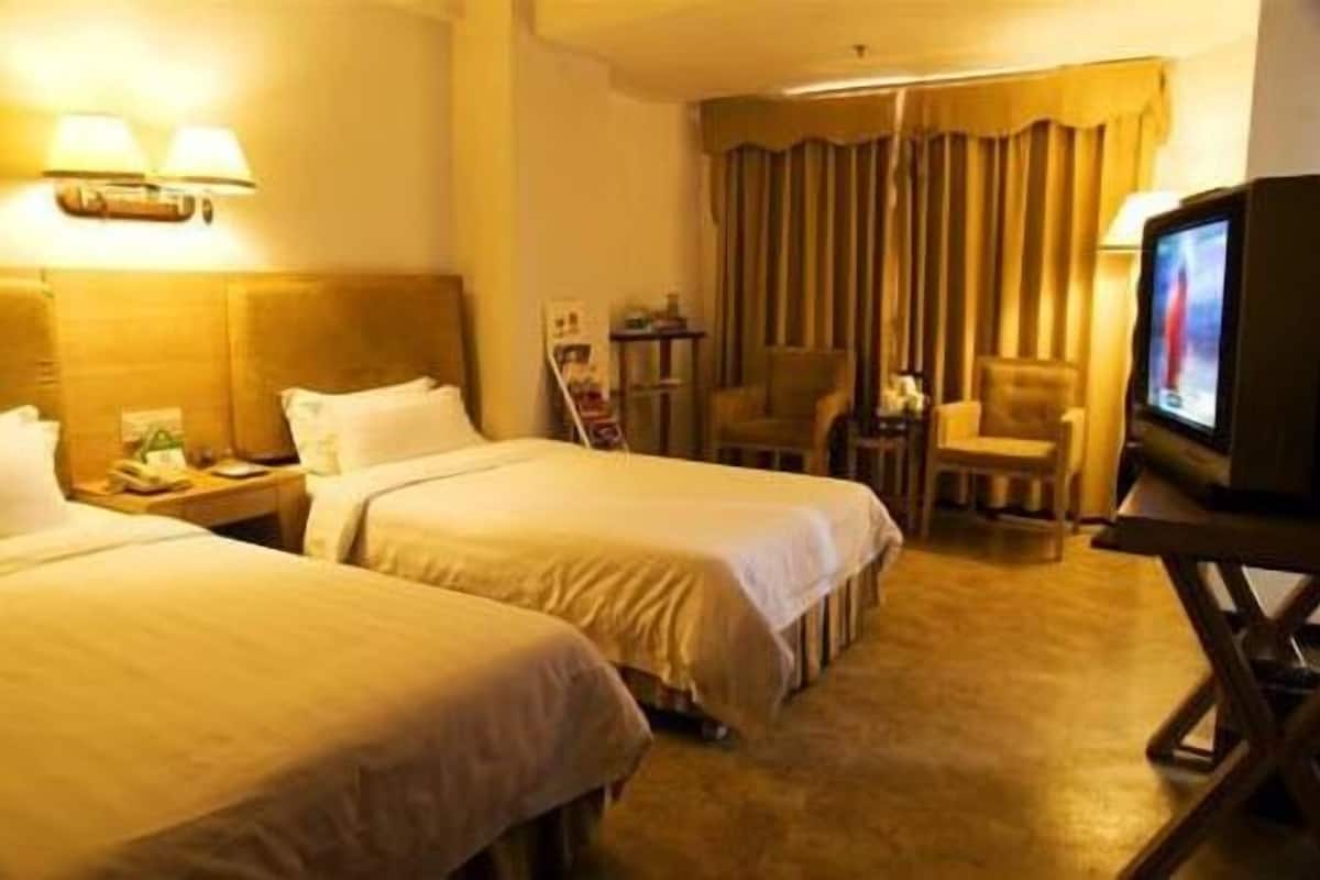 A hotel room with two beds, a television, a desk, and a chair.