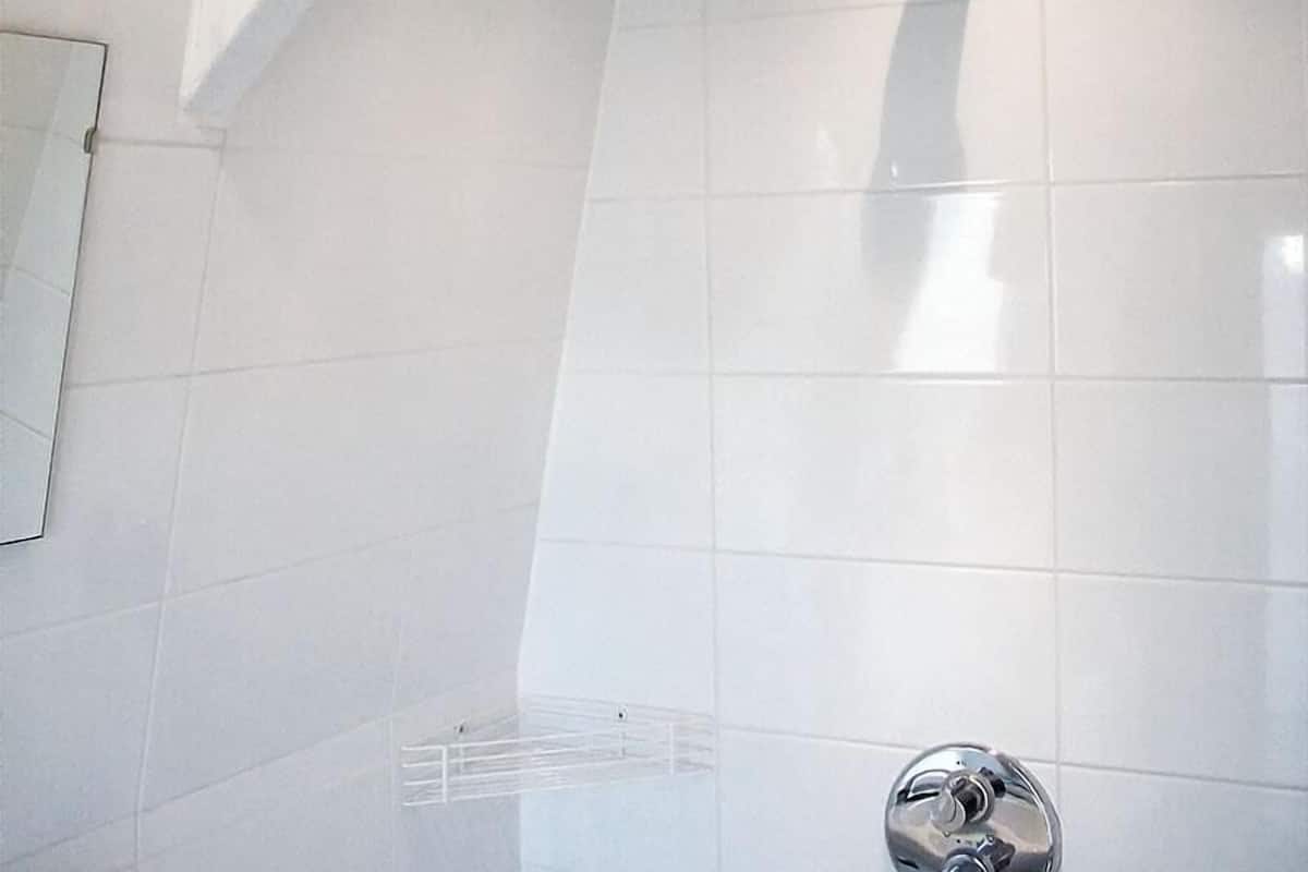 Ein modernes Badezimmer mit weißen Fliesen, einer Dusche und einem sichtbaren Handtuchhalter.