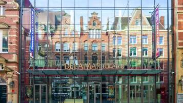 The Delamart Theater with a glass facade reflecting surrounding buildings.