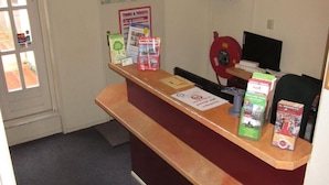 Ein Empfangstresen mit Informationsbroschüren, einer Karte und einem Computermonitor.