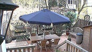 Ein Terrassenbereich im Freien mit Tisch und Stühlen, umgeben von Blumentöpfen und einem Holzzaun.