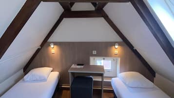 A small, cozy room with two single beds, a desk, and a window.