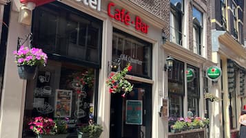 A building with a sign reading "Old Quarter Hotel Café-Bar" and a Heineken sign.