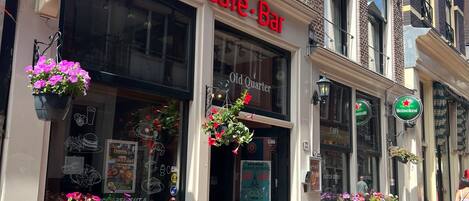 A building with a sign reading "Old Quarter Hotel Café-Bar" and a Heineken sign.