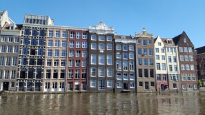 Una sequenza di edifici storici lungo un canale, caratterizzati da diversi stili architettonici e ampie finestre.