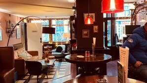 Un lobby de hotel acogedor con una recepción, asientos cómodos y vistas a la ciudad a través de amplias ventanas.