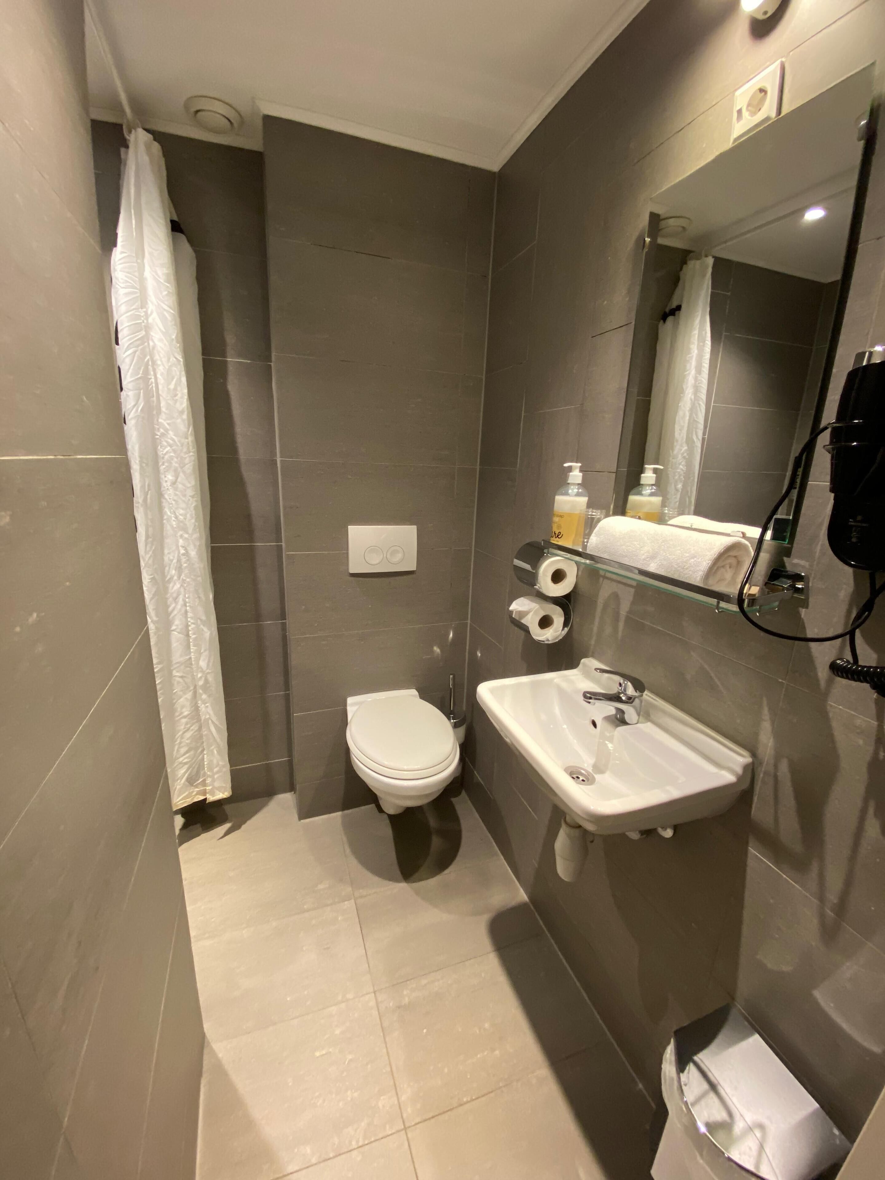 A compact bathroom with a toilet, sink, and shower area.