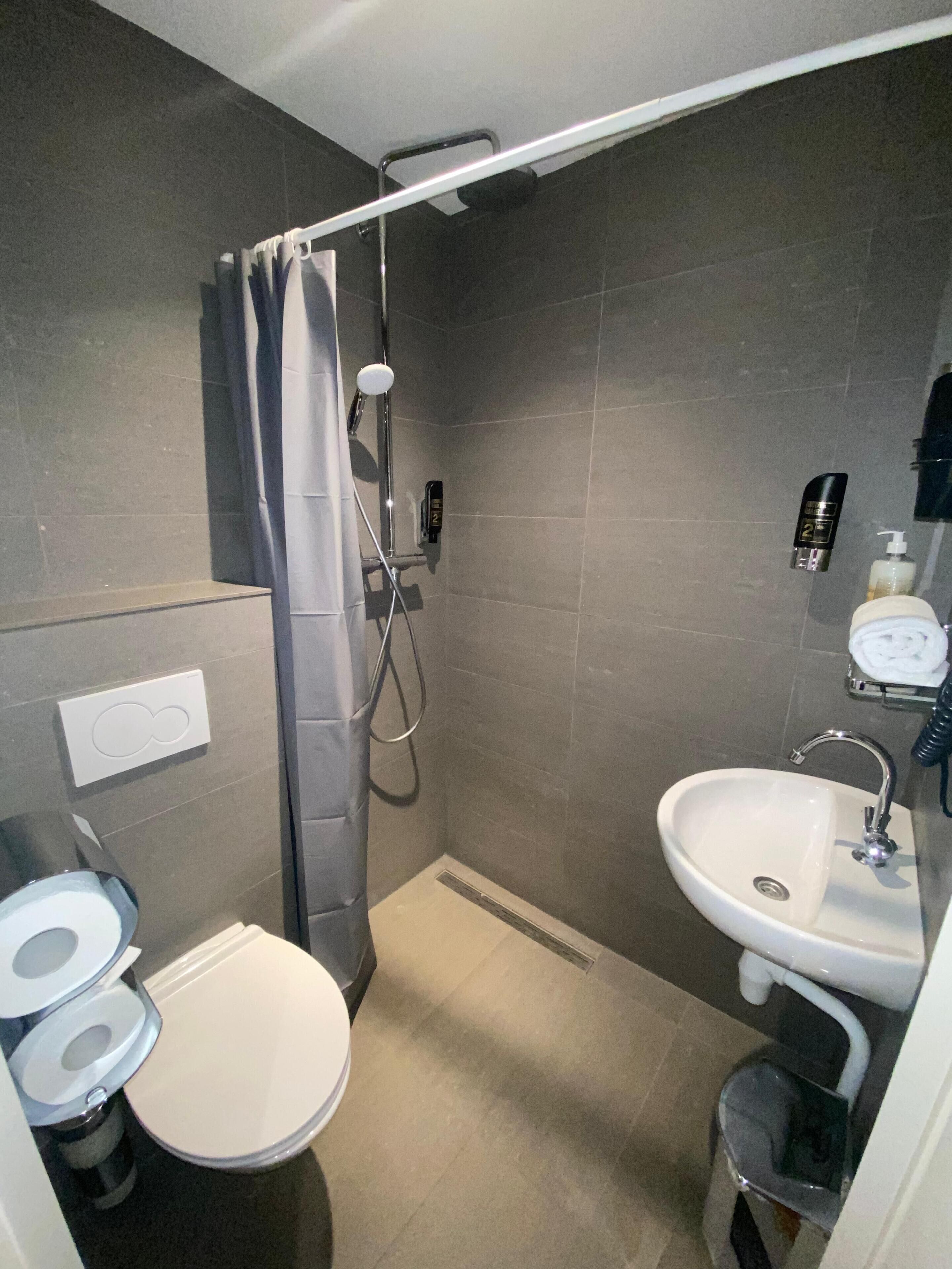 A compact bathroom with a shower, toilet, and sink.