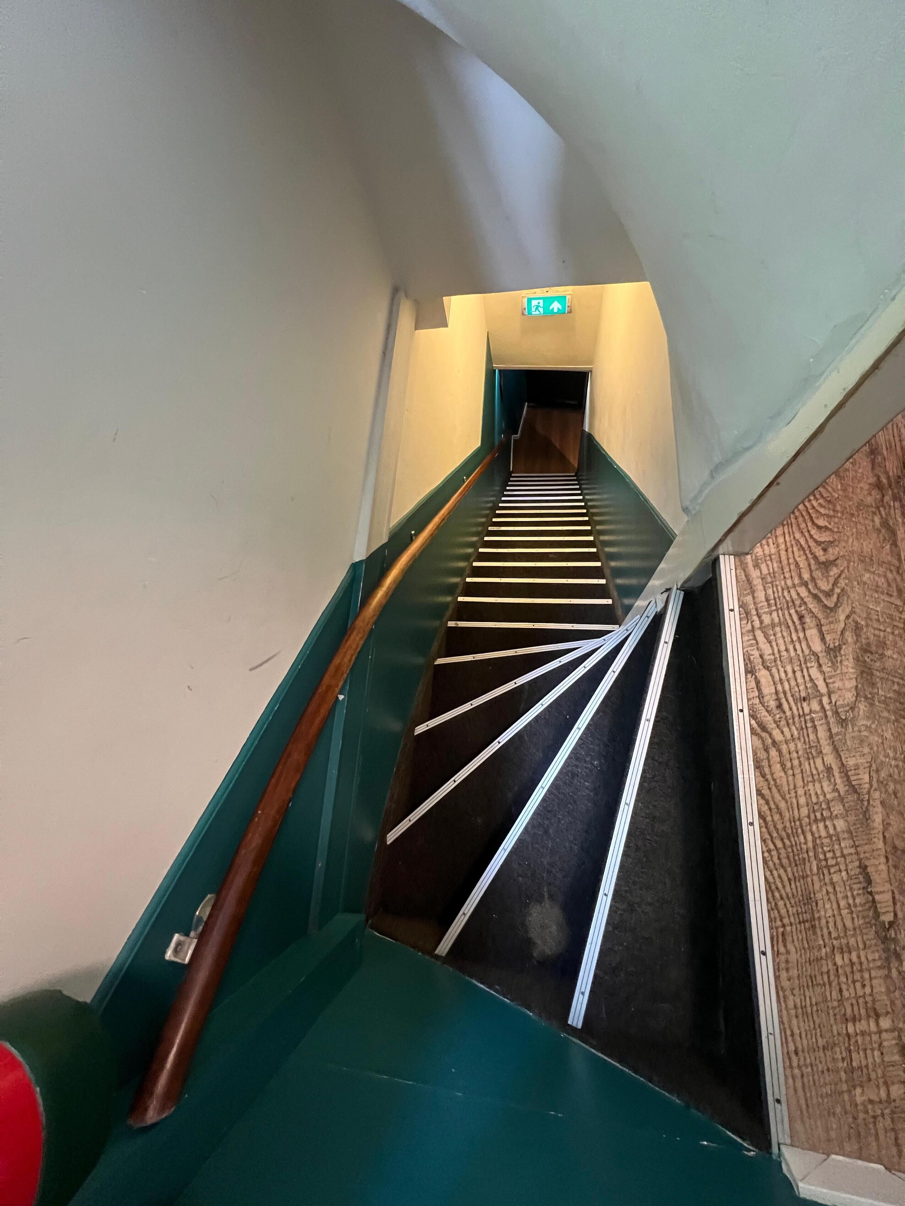A staircase with a handrail and a wooden handrail on the left.
