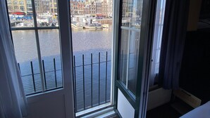 Una habitación con un amplio ventanal que da a un canal con barcos y edificios históricos.