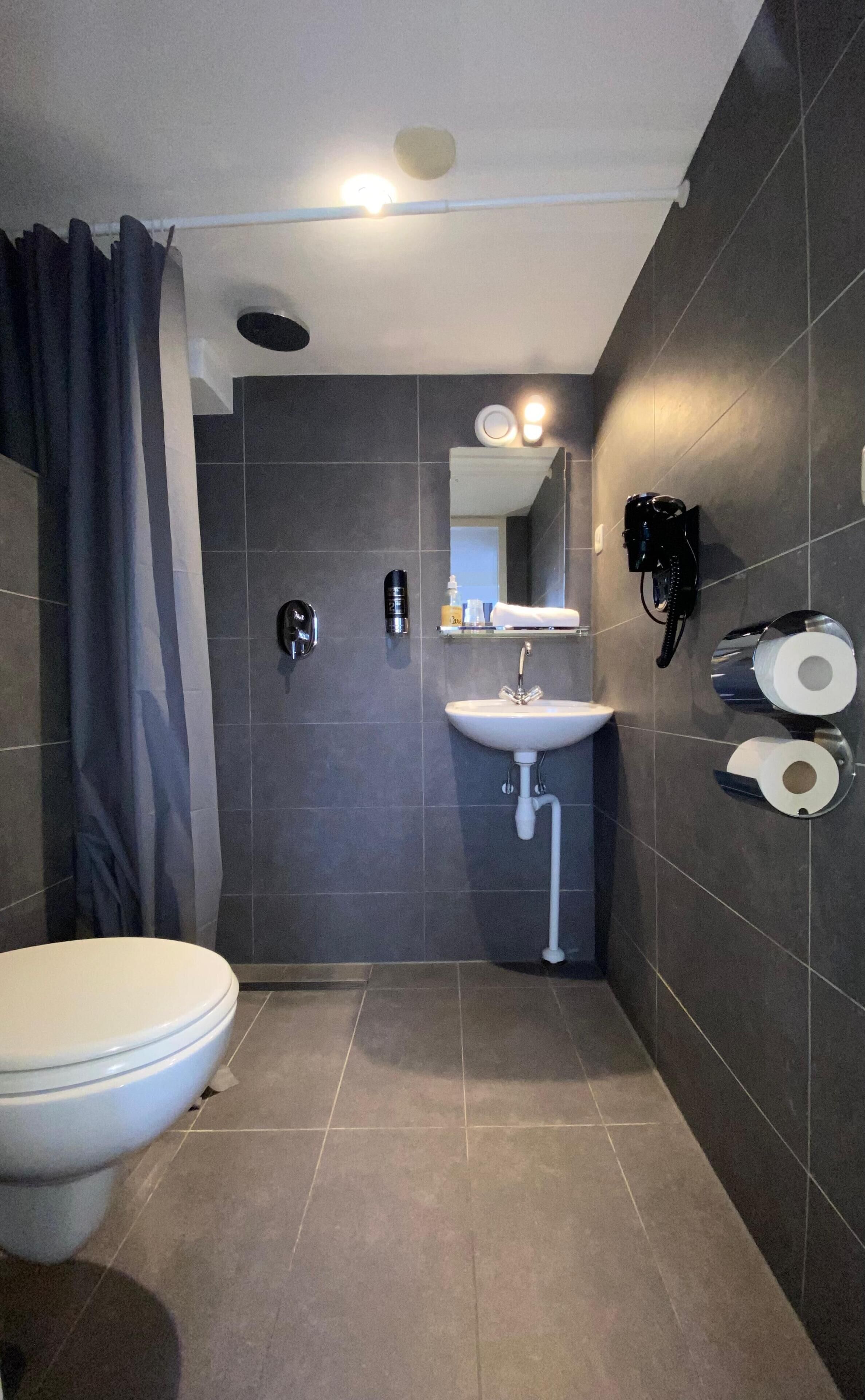 Un baño moderno con inodoro, lavamanos y zona de ducha.