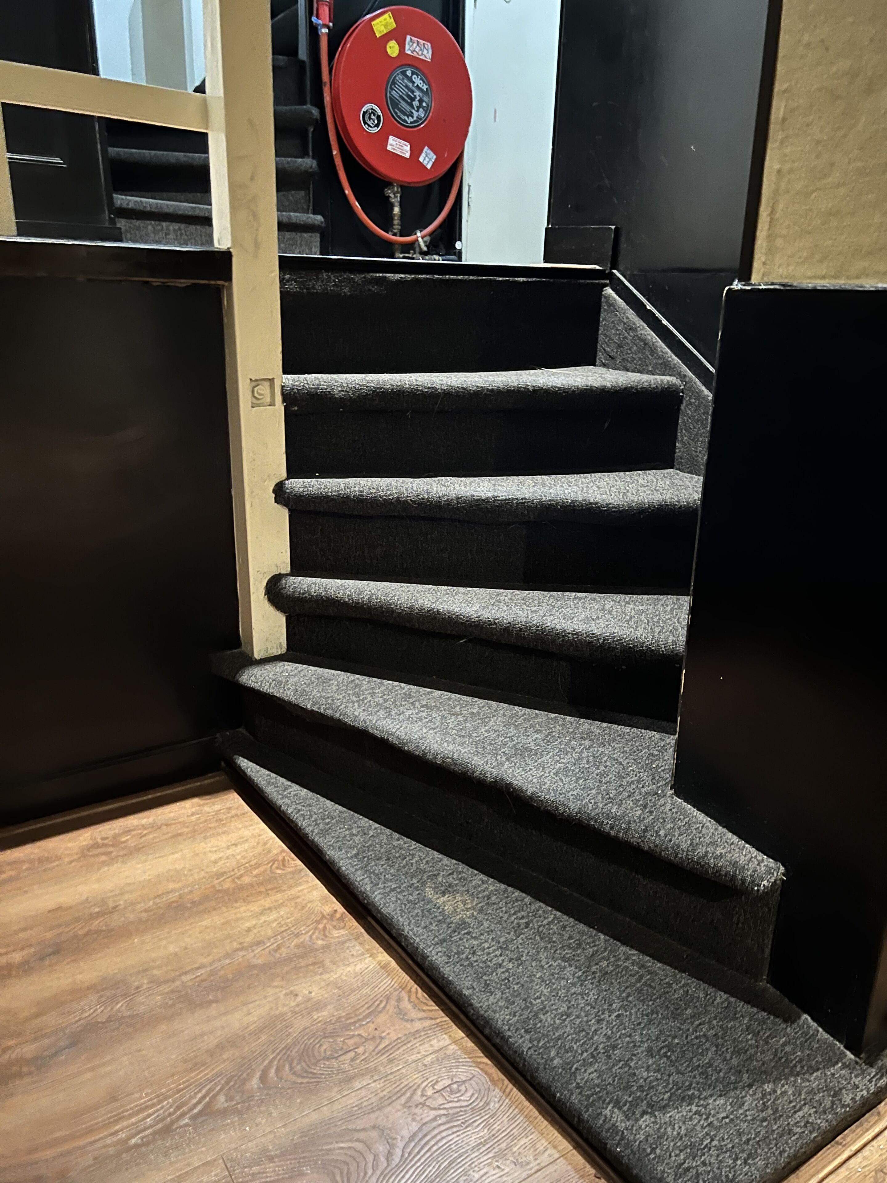 A staircase with carpeted steps leading to a landing.