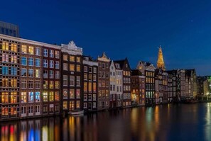 Una serie di edifici europei tradizionali lungo un canale, di notte.