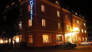 Un hôtel reconnaissable à son grand panneau « HÔTEL », à ses nombreuses fenêtres et à son entrée bien éclairée.