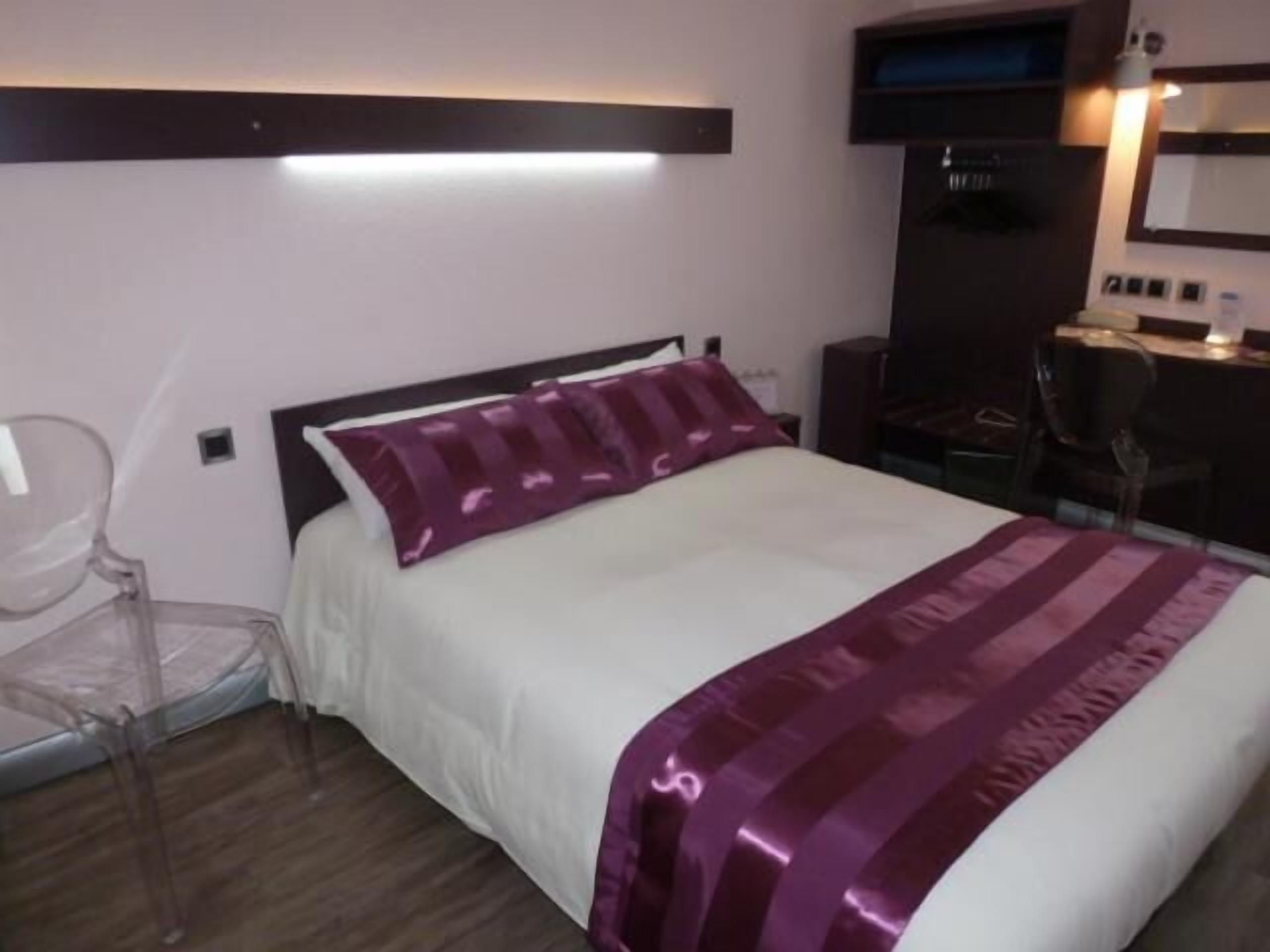 A hotel room with a bed, a desk, and a chair.