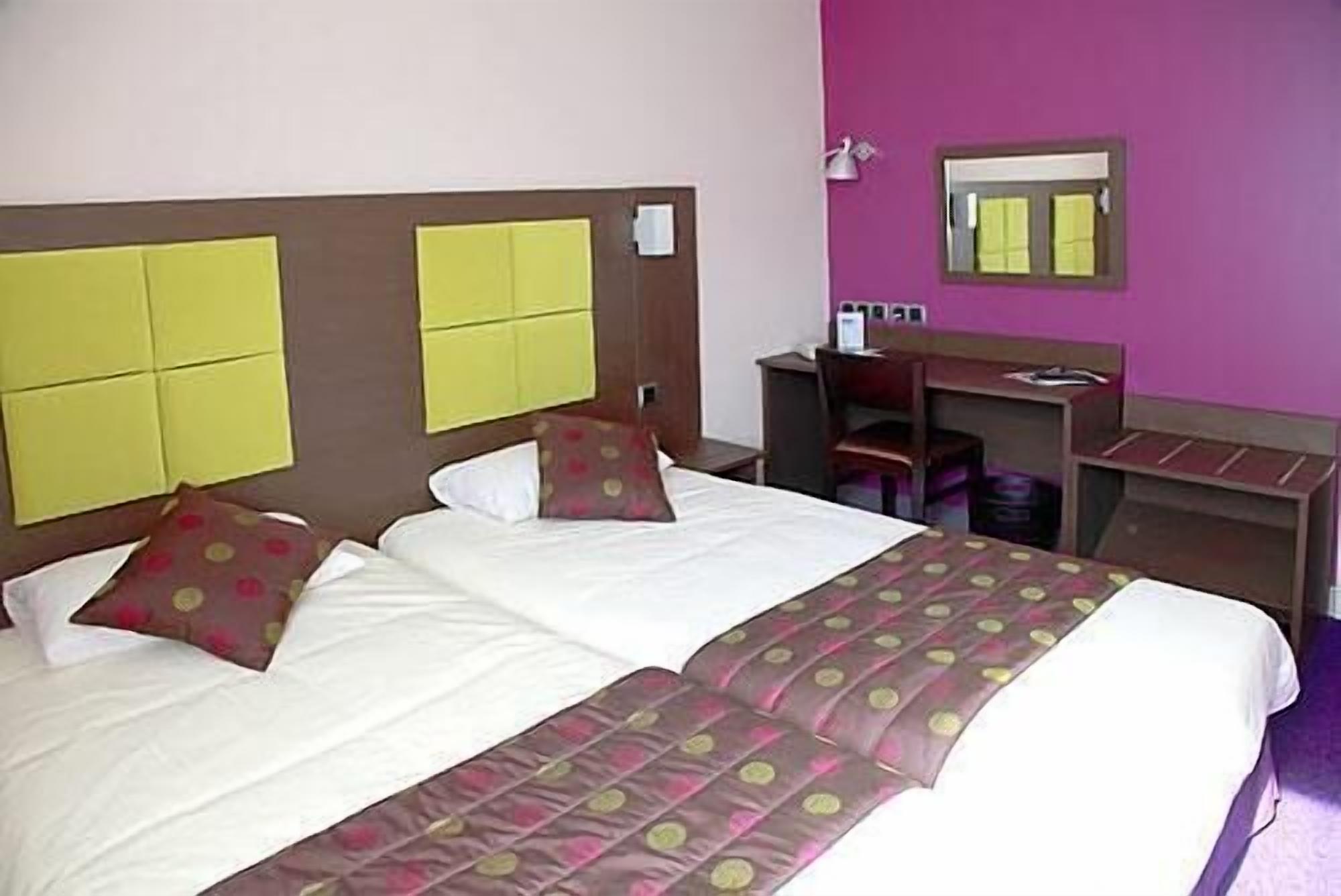 Una habitación de hotel con una cama, un escritorio y una silla.
