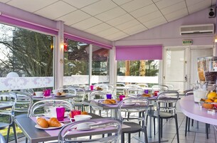 Um café com mesas ao ar livre, cadeiras e vista para árvores e edifícios.