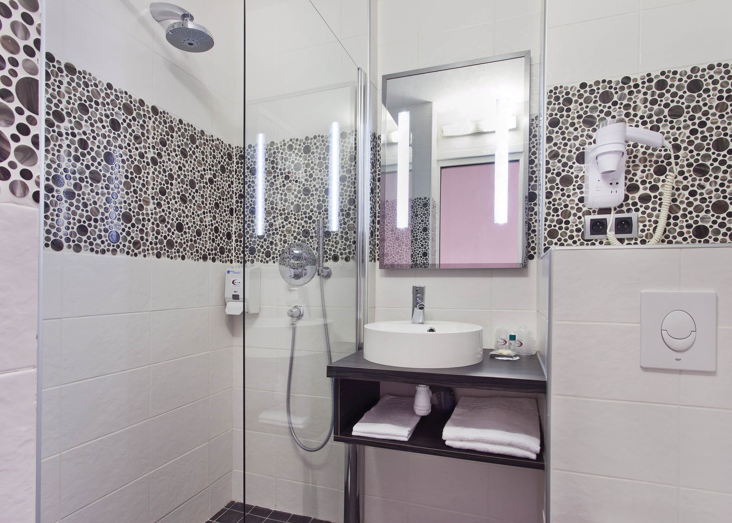 A modern bathroom with a glass-enclosed shower, a white sink, and a mirror above it.