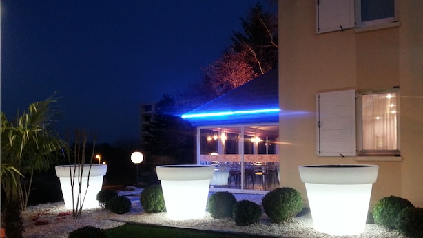 Un edificio de diseño moderno con fachada de vidrio y una tira de luz de neón azul.