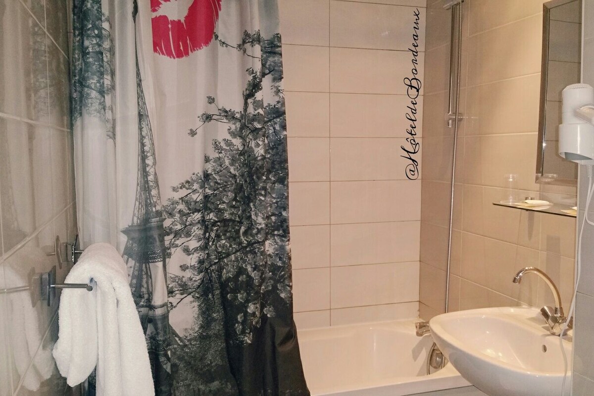A bathroom with a bathtub, a sink, and a shower curtain with a floral design.