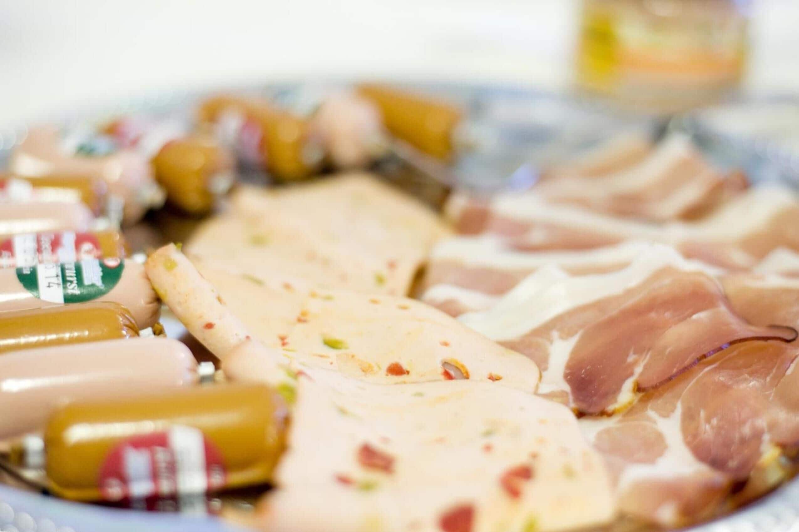 A variety of packaged food items, including sausages and cured meats, arranged on a plate.