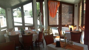 Un restaurant avec des tables dressées, de grandes fenêtres et une statue représentant une figure.