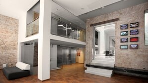 A modern interior with a mezzanine level, a staircase, and a wall with framed pictures. - Onix Liceo (Barcelona)