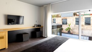 A modern hotel room with a large bed, a flat-screen TV mounted on the wall, a small desk with a chair, and a view of the city through large windows. - Onix Liceo (Barcelona)