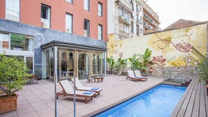 A swimming pool with lounge chairs, a glass-enclosed area, and a decorative mural on the adjacent wall. - Onix Liceo (Barcelona)