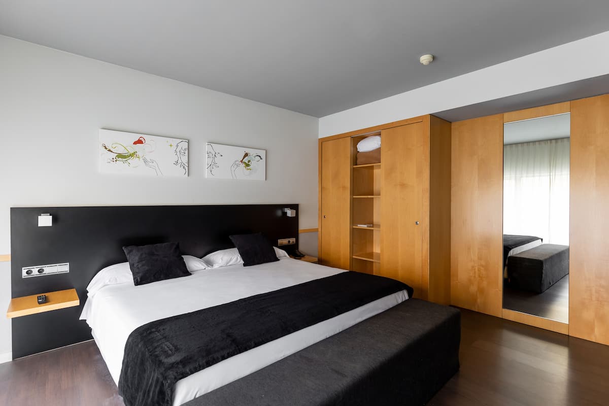 Un dormitorio moderno con una cama grande, un armario de madera y obras de arte en la pared.