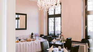 A dining area with a chandelier, tables set for four, and a buffet setup. - Boutique Hotel Villa Oberkassel (Düsseldorf)