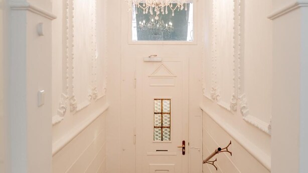 A hallway with a white door, a red carpet, and a chandelier. - Boutique Hotel Villa Oberkassel (Düsseldorf)