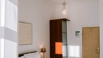 A neatly made bed with white linens, a bedside lamp, and a framed abstract artwork on the wall.