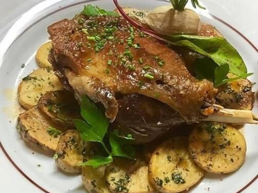 A plate with roasted meat, potatoes, and greens.